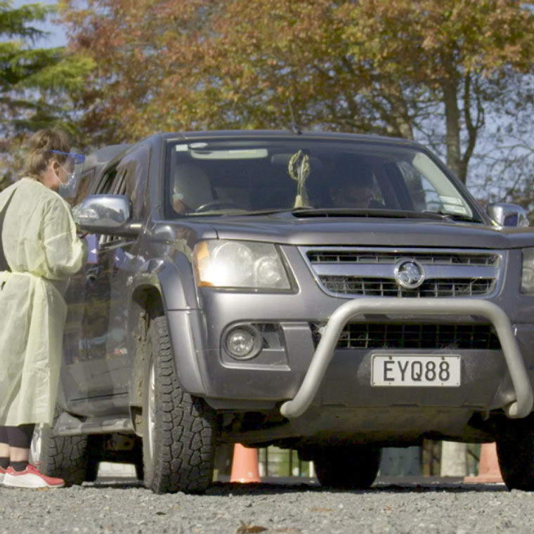 A woman in PPE standing next to a ute